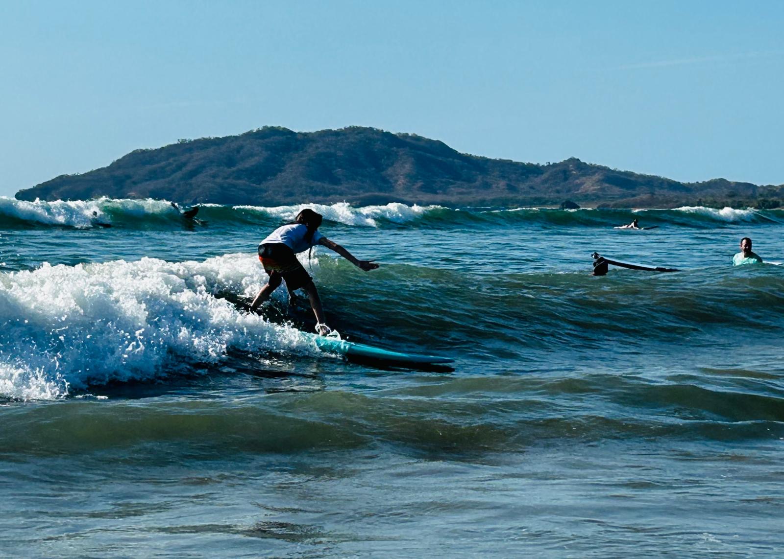 Surfer riding a wave with the coastline behind